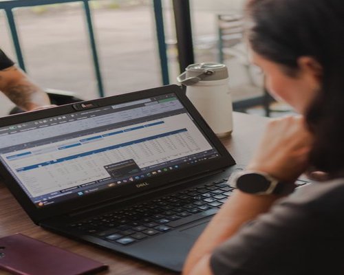 Person working on a laptop with a water bottle nearby